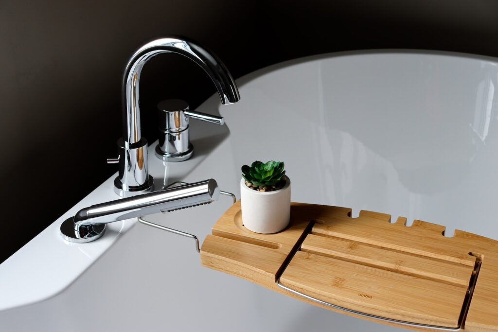 a bathroom sink with a wooden tray holding a succulent