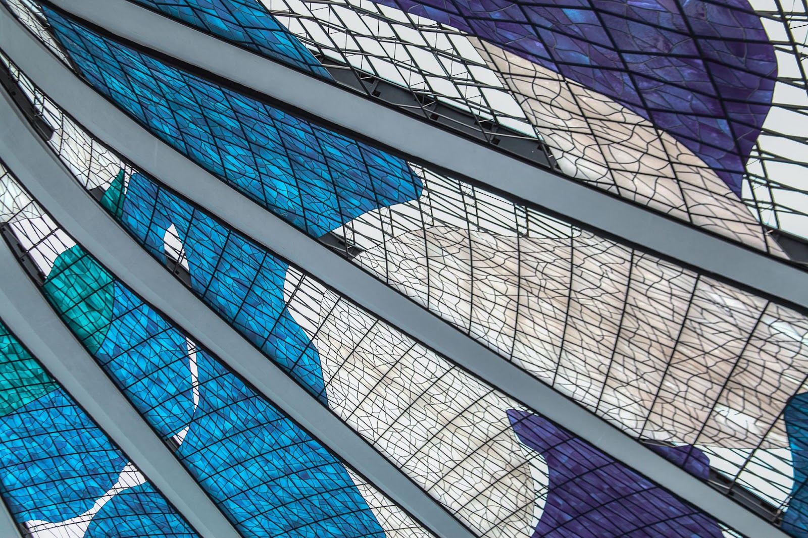 Desenhos internos dos vitrais da Catedral Metropolitana Nossa Senhora Aparecida. Os grandes painéis situados entre os arcos têm formas orgânicas em tons de azul e branco.