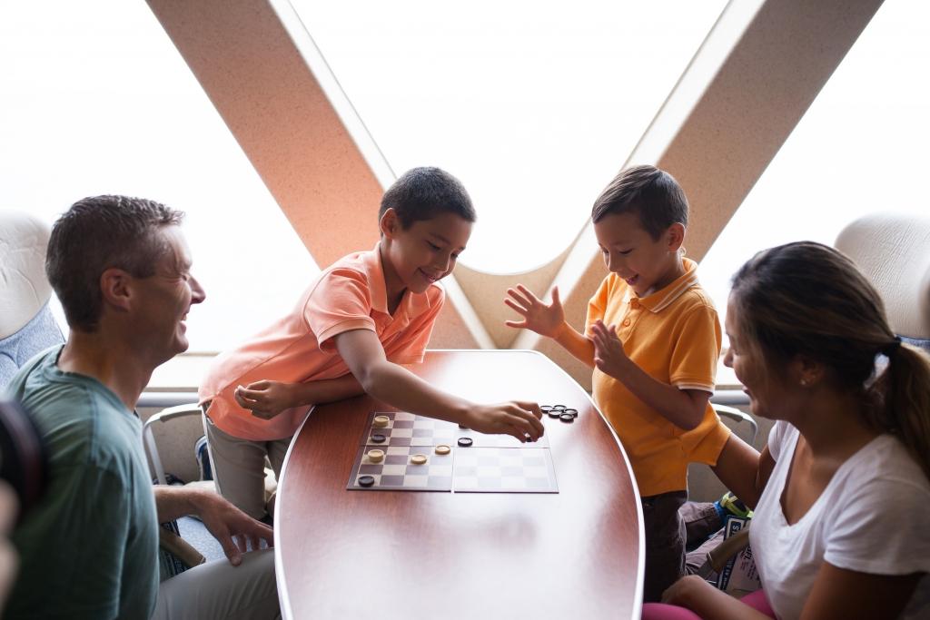 A family plays a game of checkers together while laughing