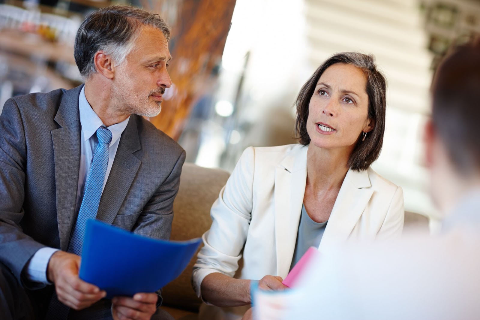 A close-up of a group of business consultants finalizing their proposal, with only the third person's back visible.