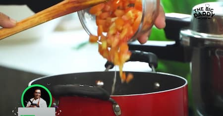  Tomatoes and spices being added to the pan, creating a rich and flavorful masala.