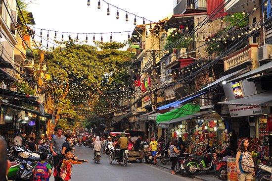 A street with many people and scooters

Description automatically generated