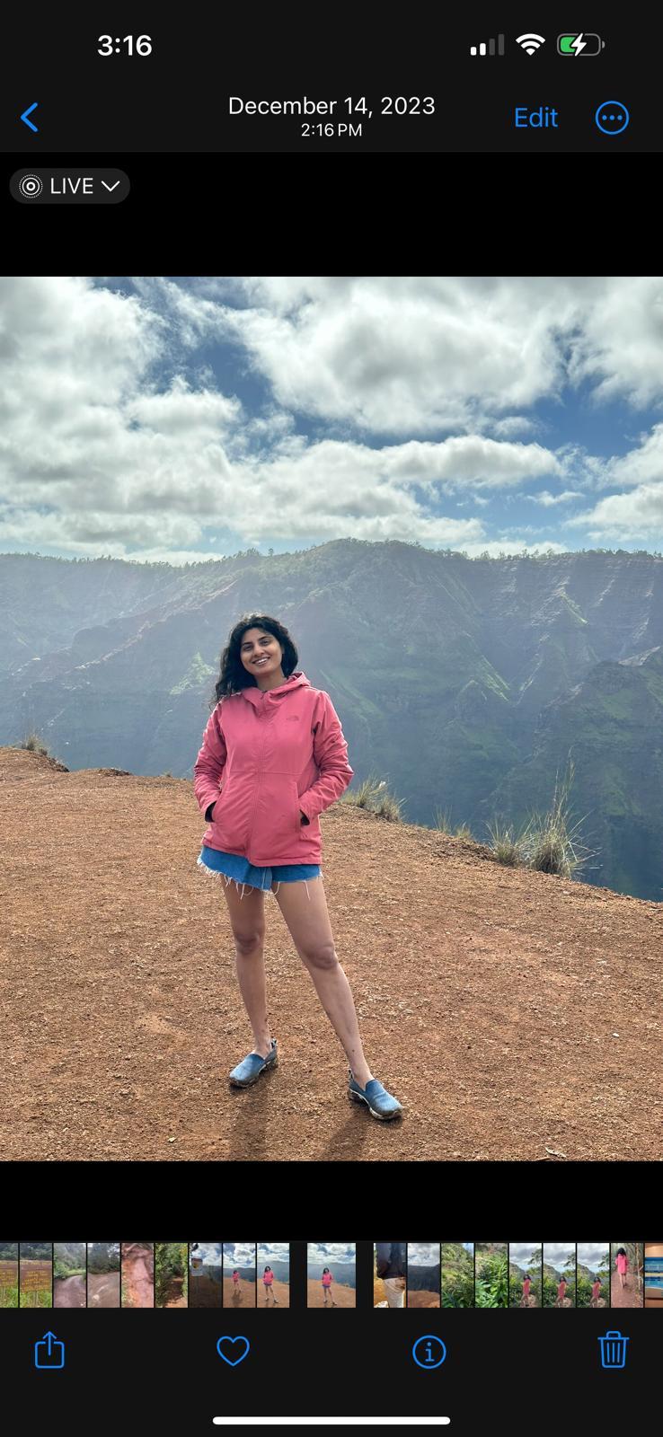 A person standing on a hill with mountains in the background

Description automatically generated