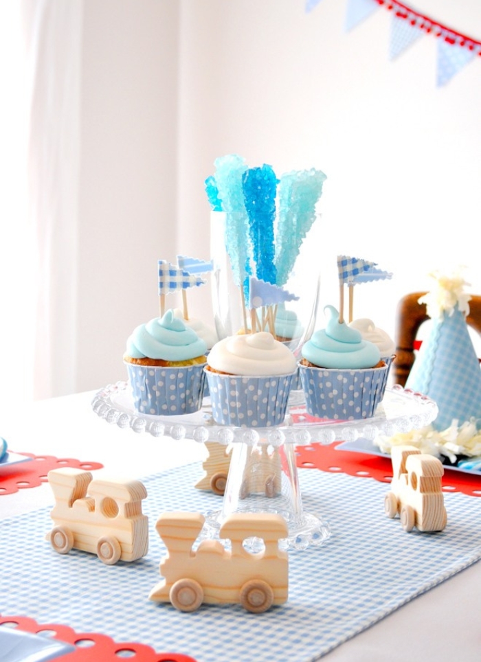 blue and white cupcakes on table with wooden train