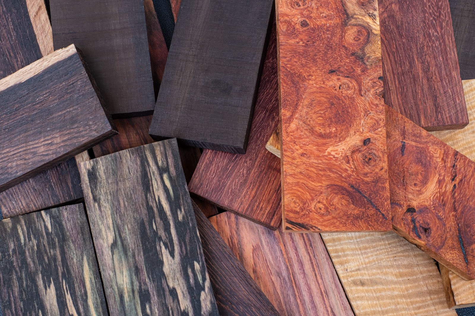 A set of rosewood, ebony, black, and white wood timber blocks showcasing different natural colors and grain patterns.