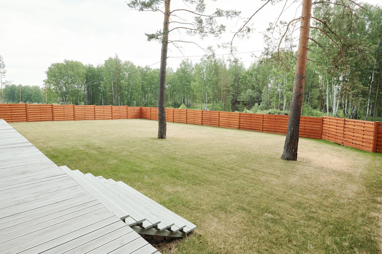A spacious backyard, surrounded by a brown fence, provides ample room for relaxation and outdoor activities, offering a serene environment for enjoying nature's beauty.