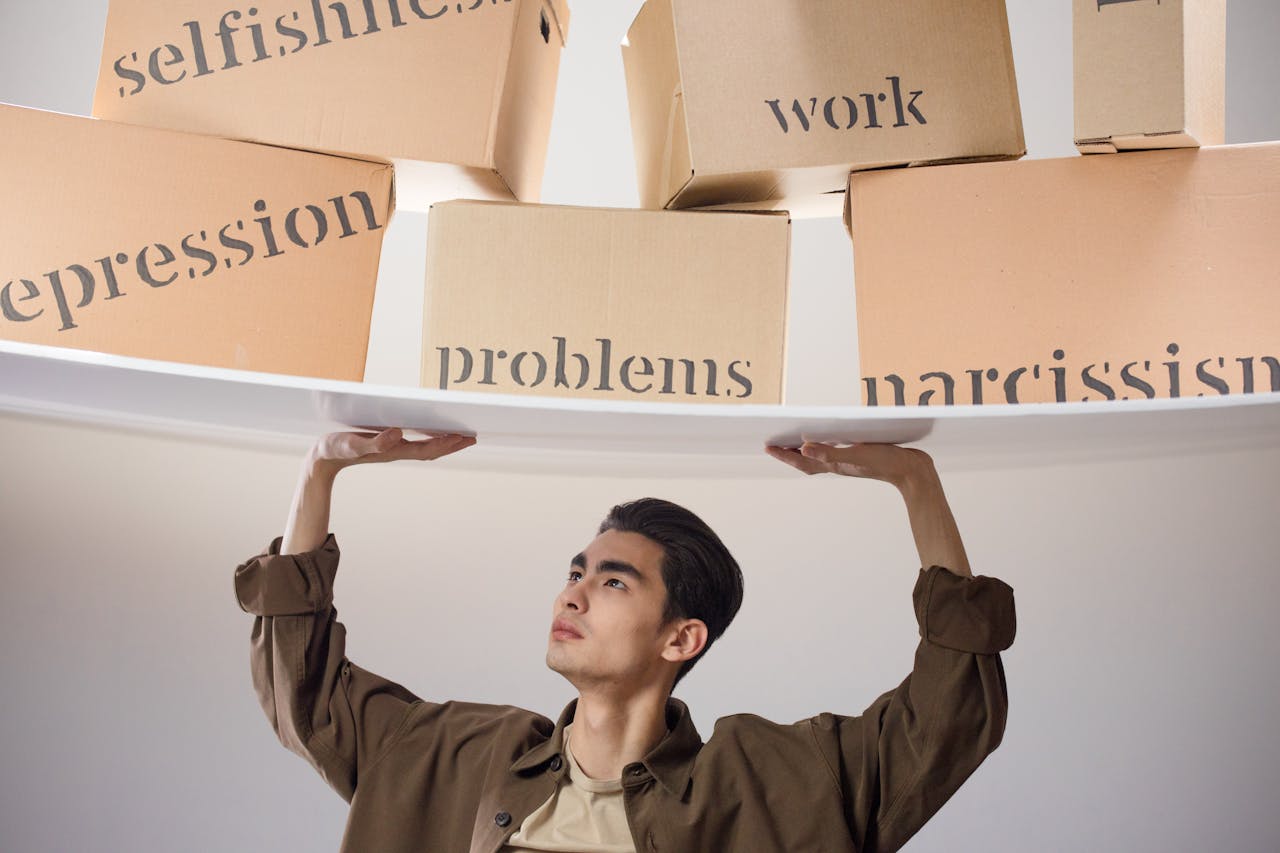 A man on top of stacked boxes, depicting self-esteem, depression, work, and problems.