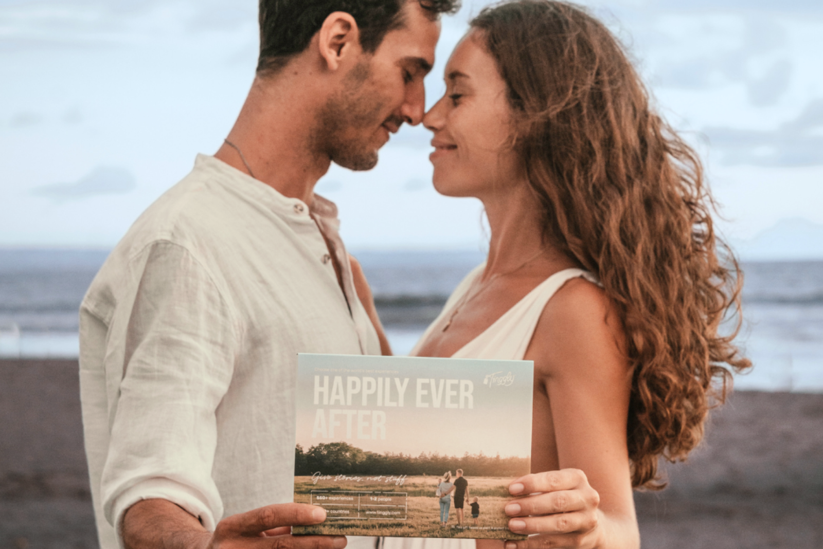 A happy couple on a honeymoon holding Tinggly's Happily Ever After experience gift box