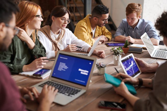 A team of professionals sitting together  with laptops, likely tracking or monitoring progress toward goals.