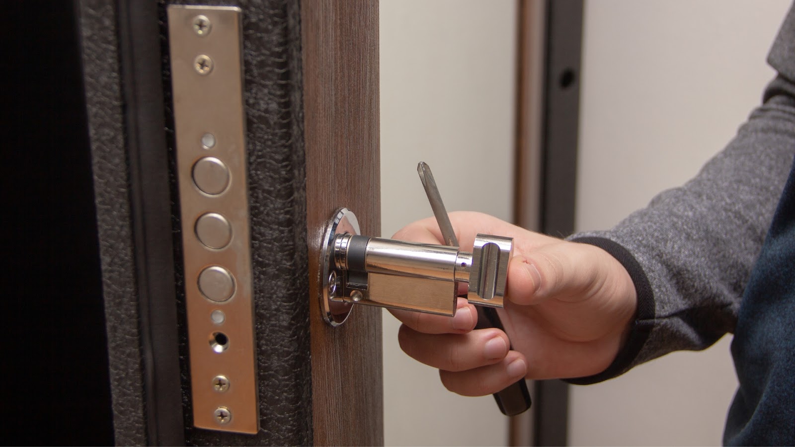A residential locksmith performs lock rekey services by using a tool to adjust the internal components of a door lock.