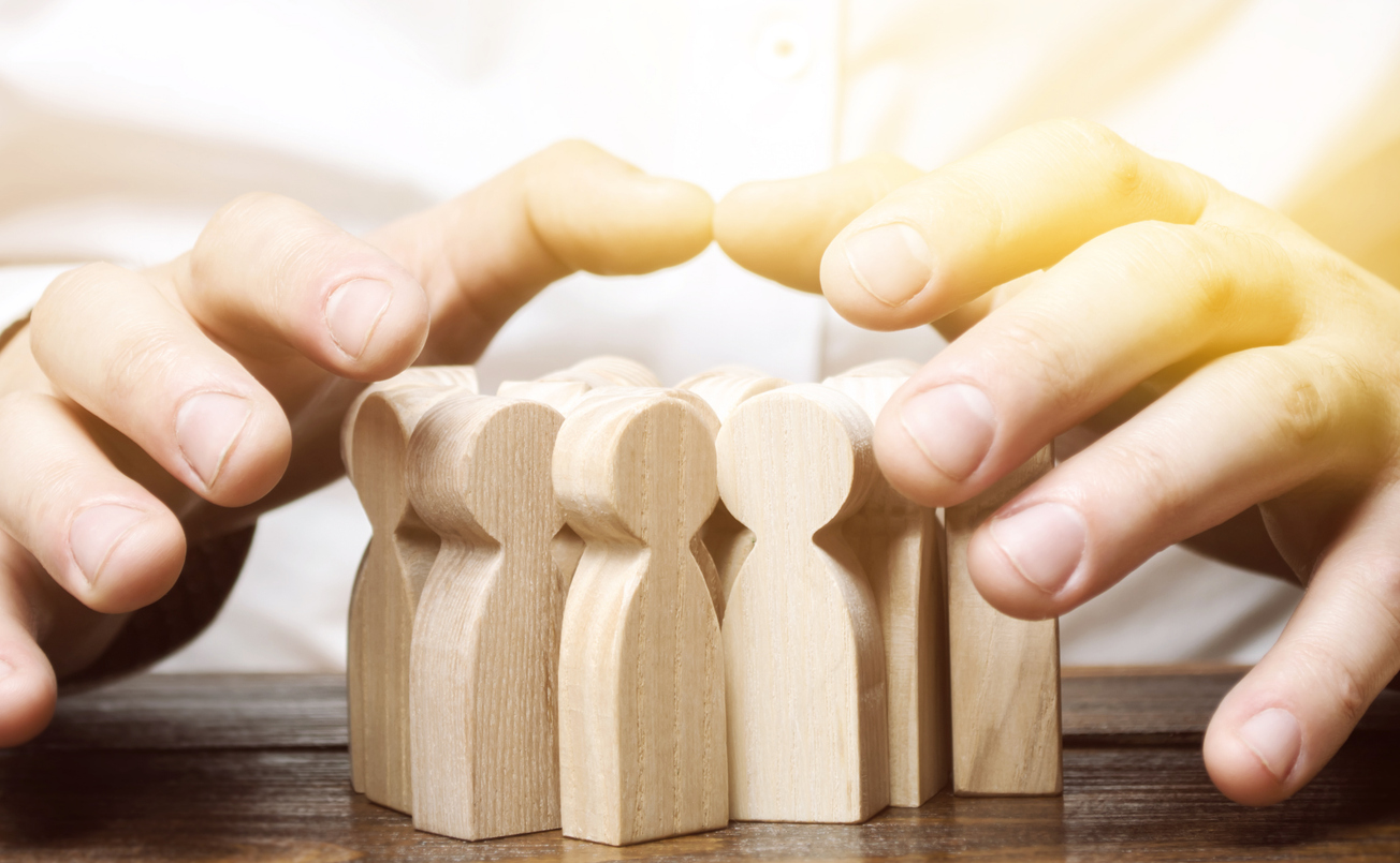 man's hands protecting wooden human blocks