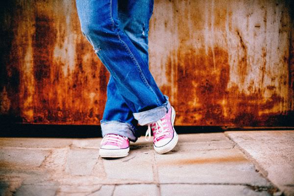 Eine Frau in Ripped Jeans in dunklem blau und rosa Sportschuhen