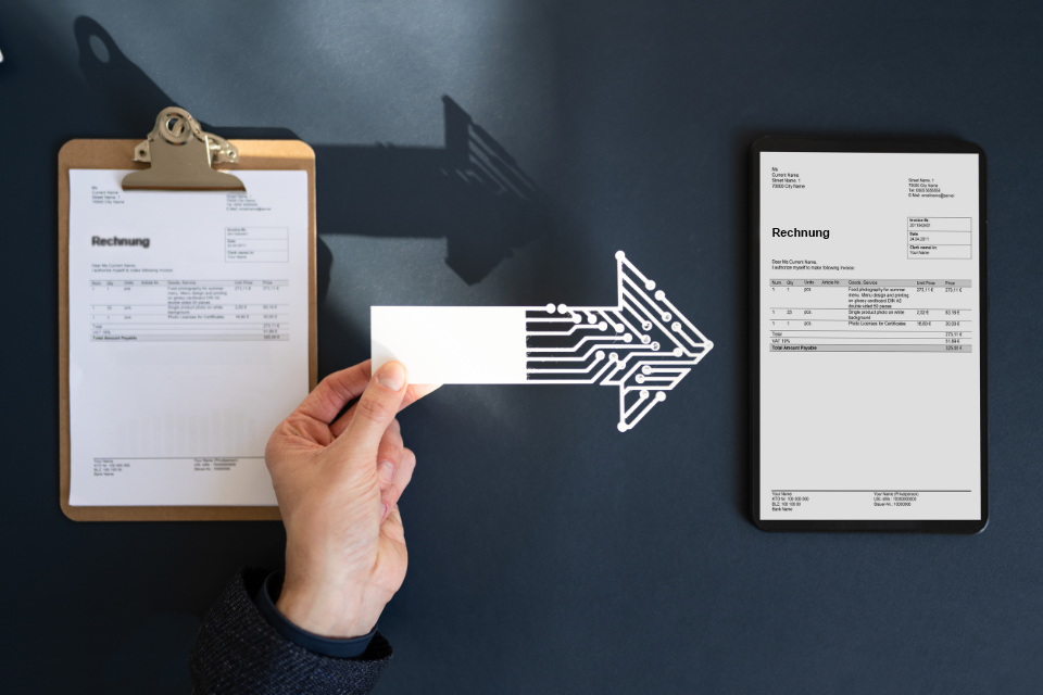Jemand hält einen Pfeil ins Bild der von einer Papierrechnung auf eine elektronische Rechnung zeigt