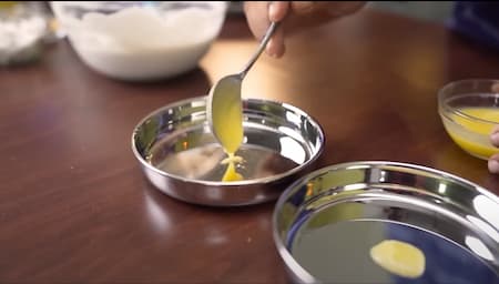 Thatte Idli moulds being greased with ghee before pouring the batter.