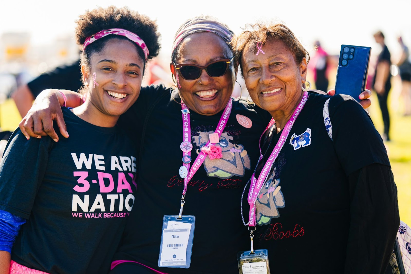 Three women embracing while wearing custom-decorated t-shirts for a Susan G. Komen breast cancer fundraising walk. 