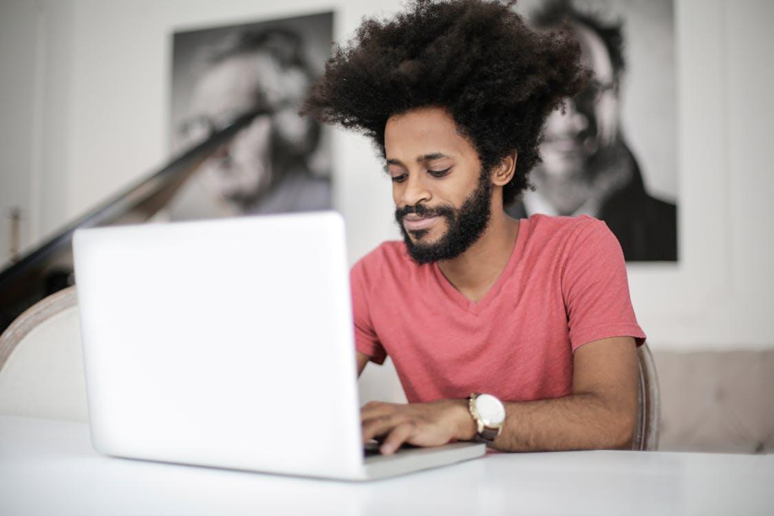 Free Man in Red Crew Neck T-shirt Using Laptop Stock Photo