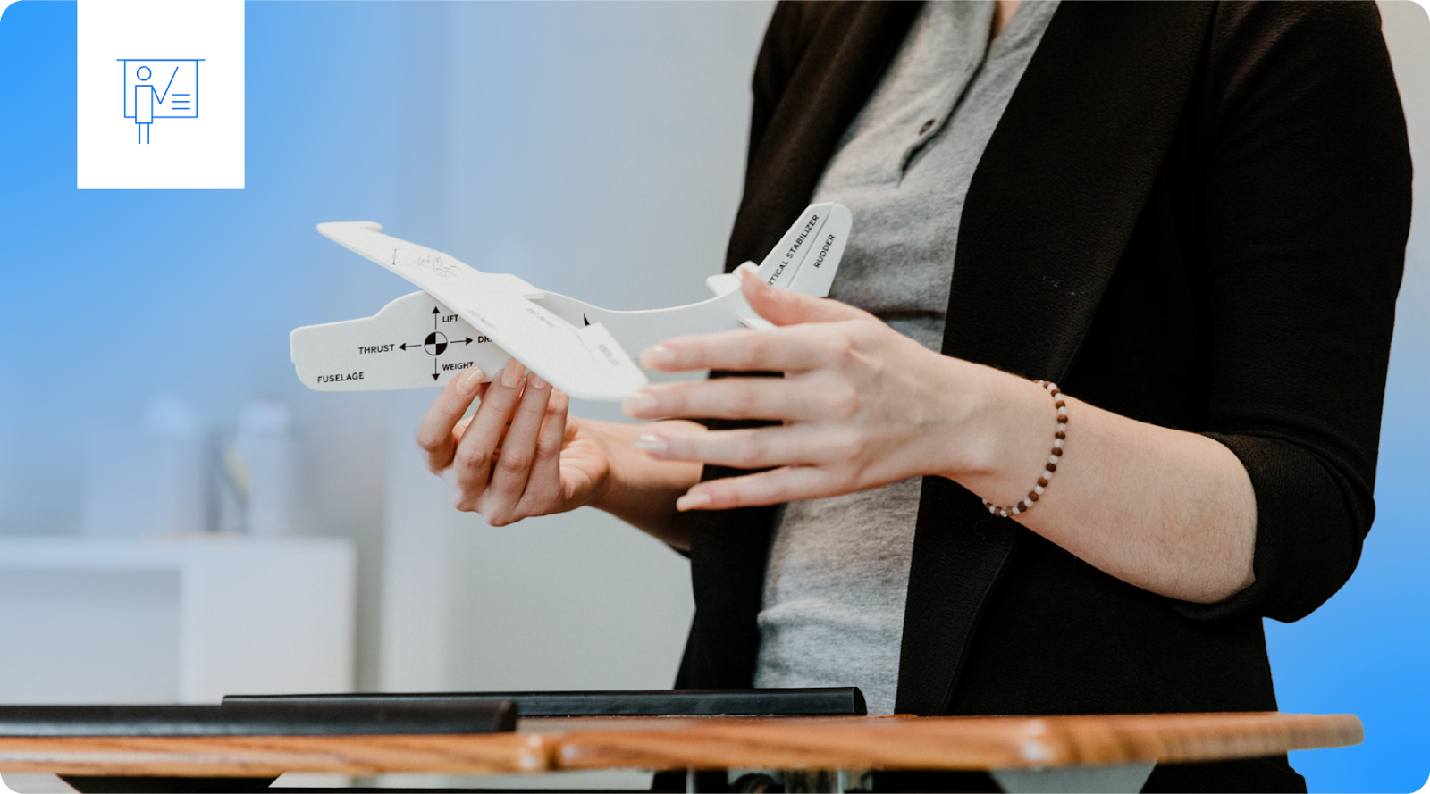 An instructor holds a model airplane to demonstrate aeronautical concepts.