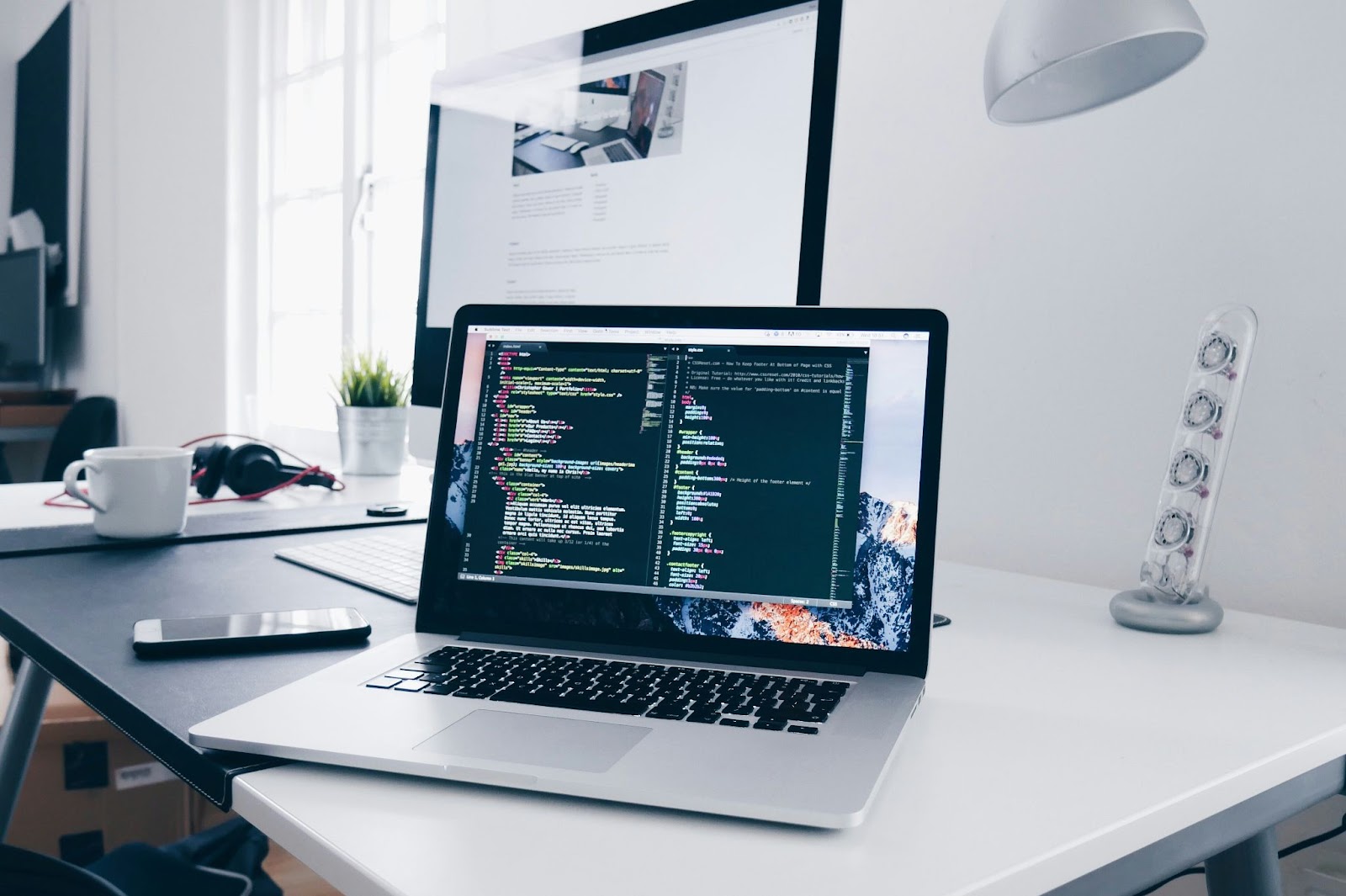 A laptop and behind it a monitor in a table or desk.