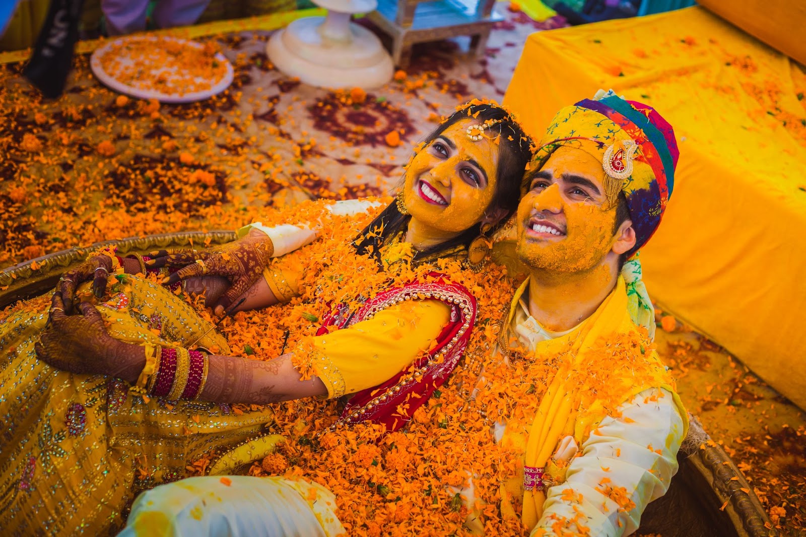Couple haldi ceremony picture - In this vibrant image, the couple is joyfully covered in turmeric paste and flowers during their haldi ceremony. Captured by a professional wedding photographer in Indore, this picture perfectly showcases the lively and colorful tradition. Known for their expertise in creative and documentary-style wedding photography, this best wedding photographer in Indore offers affordable wedding photography services. This photograph, part of the top wedding photographer's portfolio in Indore, beautifully captures the essence of this pre-wedding ritual, ideal for those hiring a wedding photographer in Indore.
