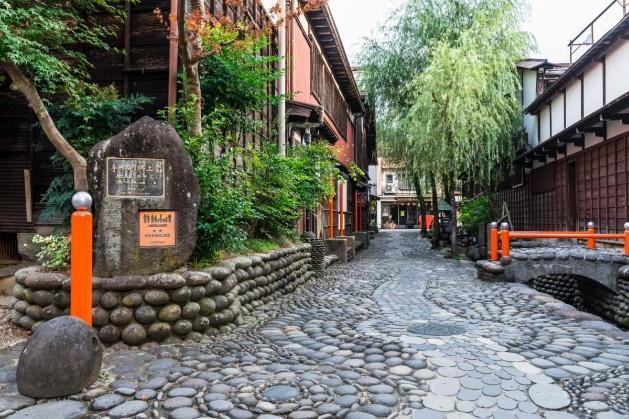 A stone street with trees and a stone sign

Description automatically generated