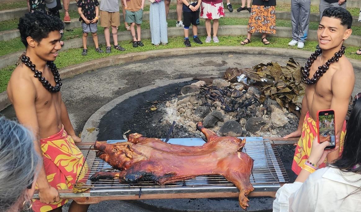 A group of people watching a pig roasting

Description automatically generated