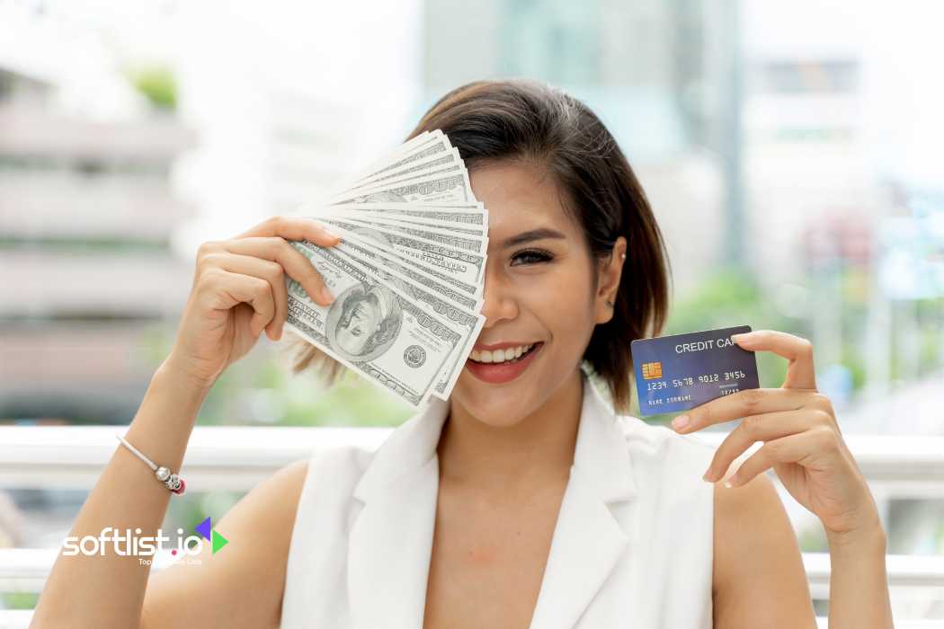 Woman holding cash and credit card, smiling outdoors