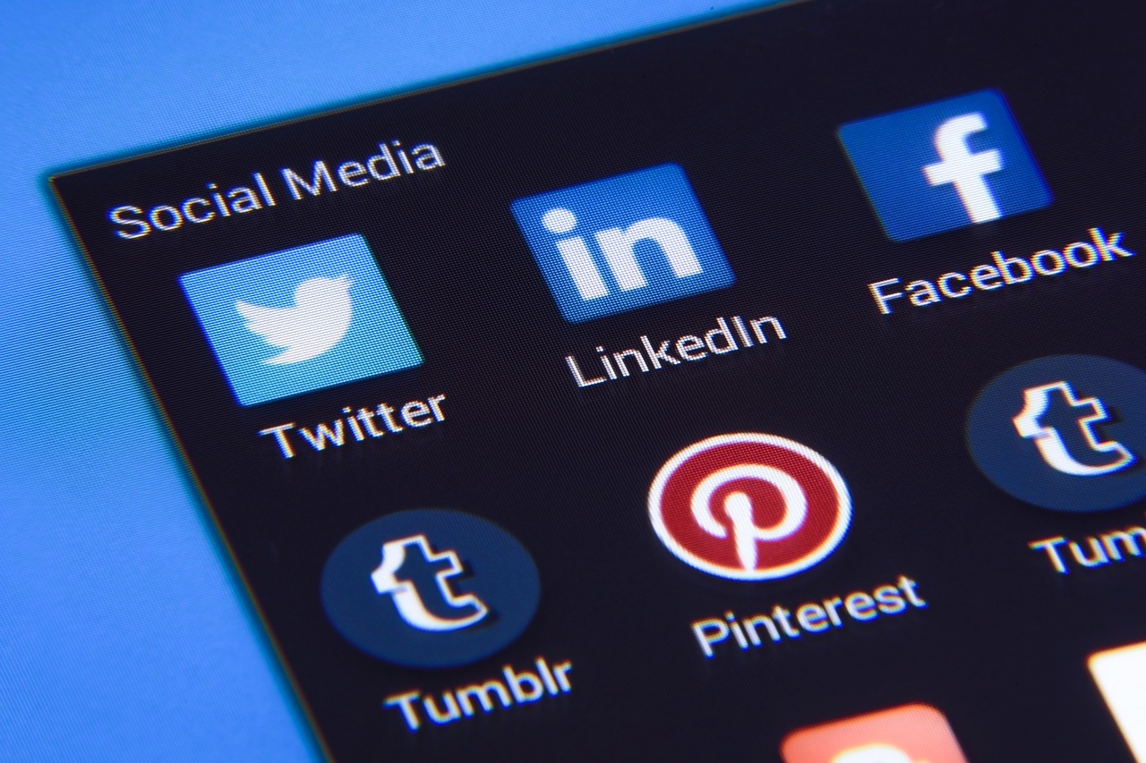 A close-up image of a phone screen displaying icons for various social media platforms, including Twitter, LinkedIn, Facebook, Tumblr, and Pinterest.