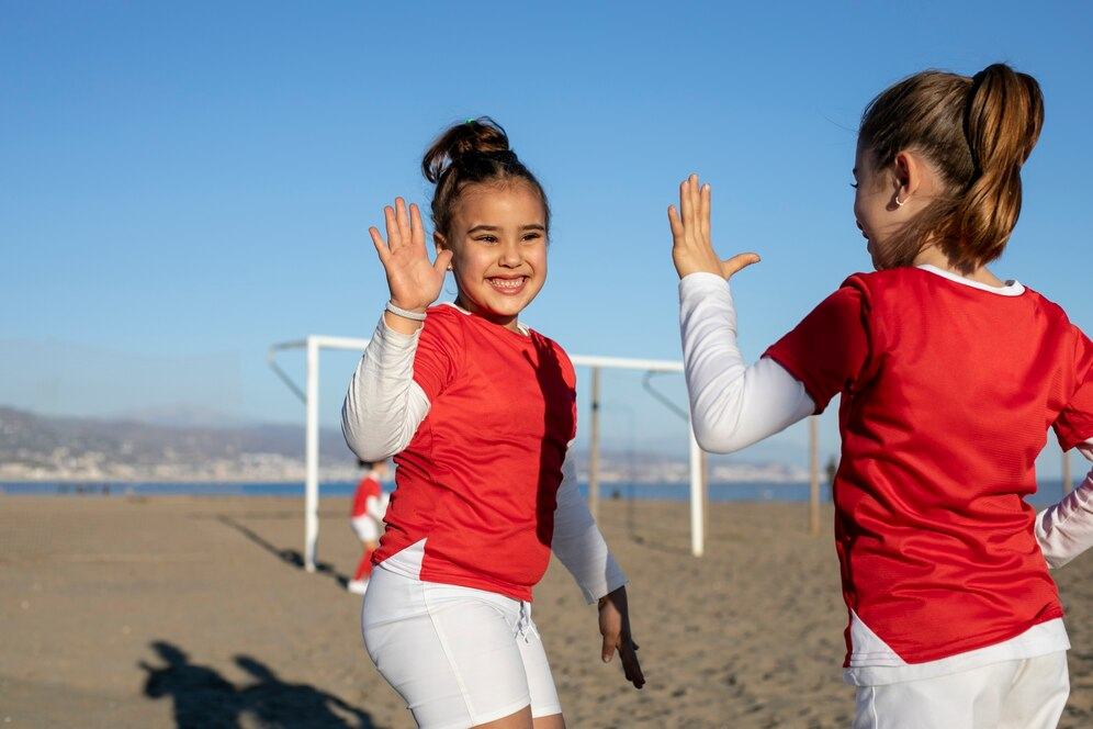 Two girls playing football in beach.