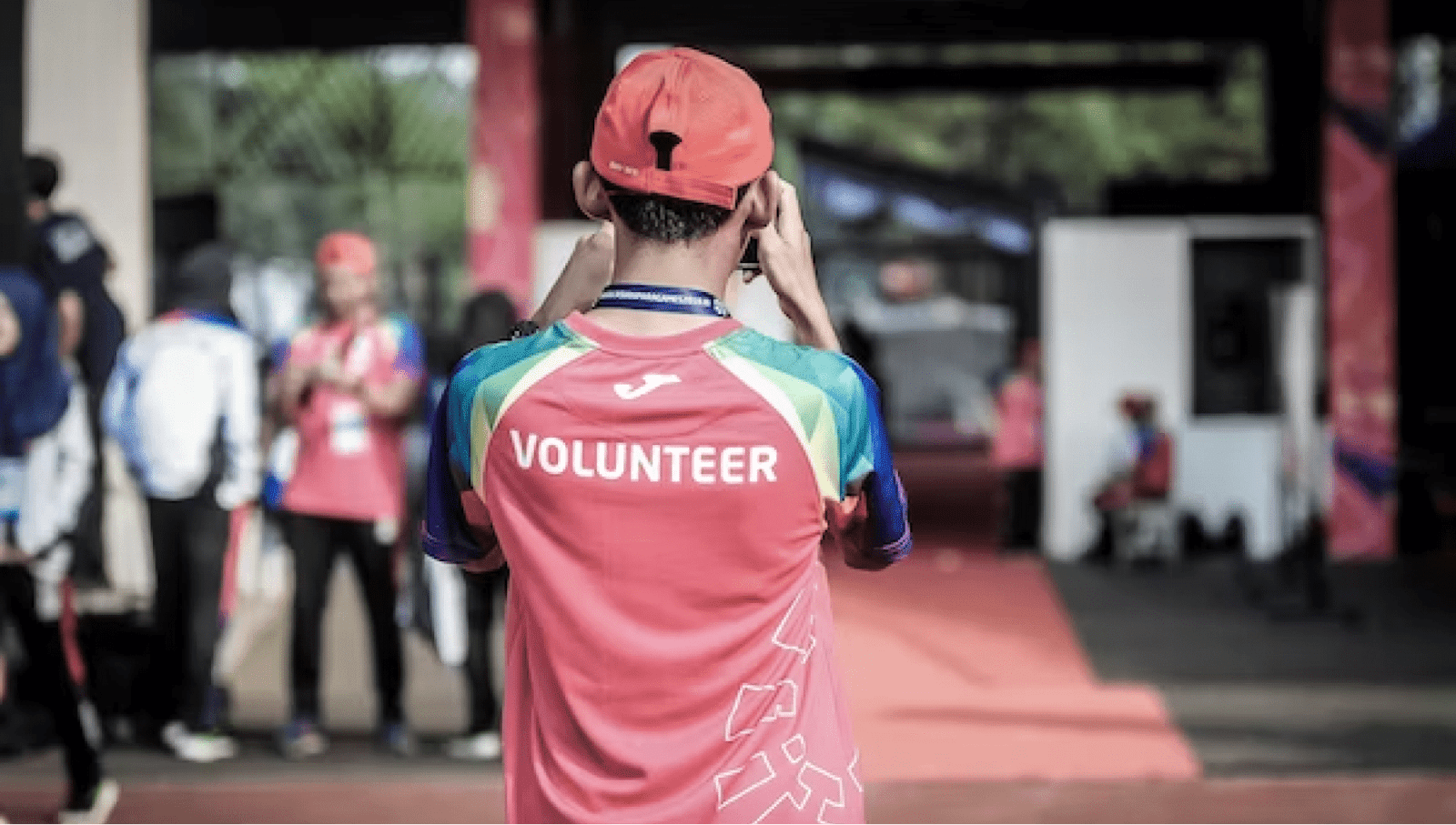 Man wearing a volunteer shirt films on his phone outside event