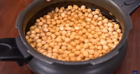 Soaked chickpeas and spices in a pressure cooker, ready to be cooked.