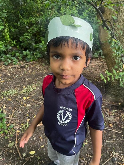 A child wearing a hat with leaves on his head

Description automatically generated