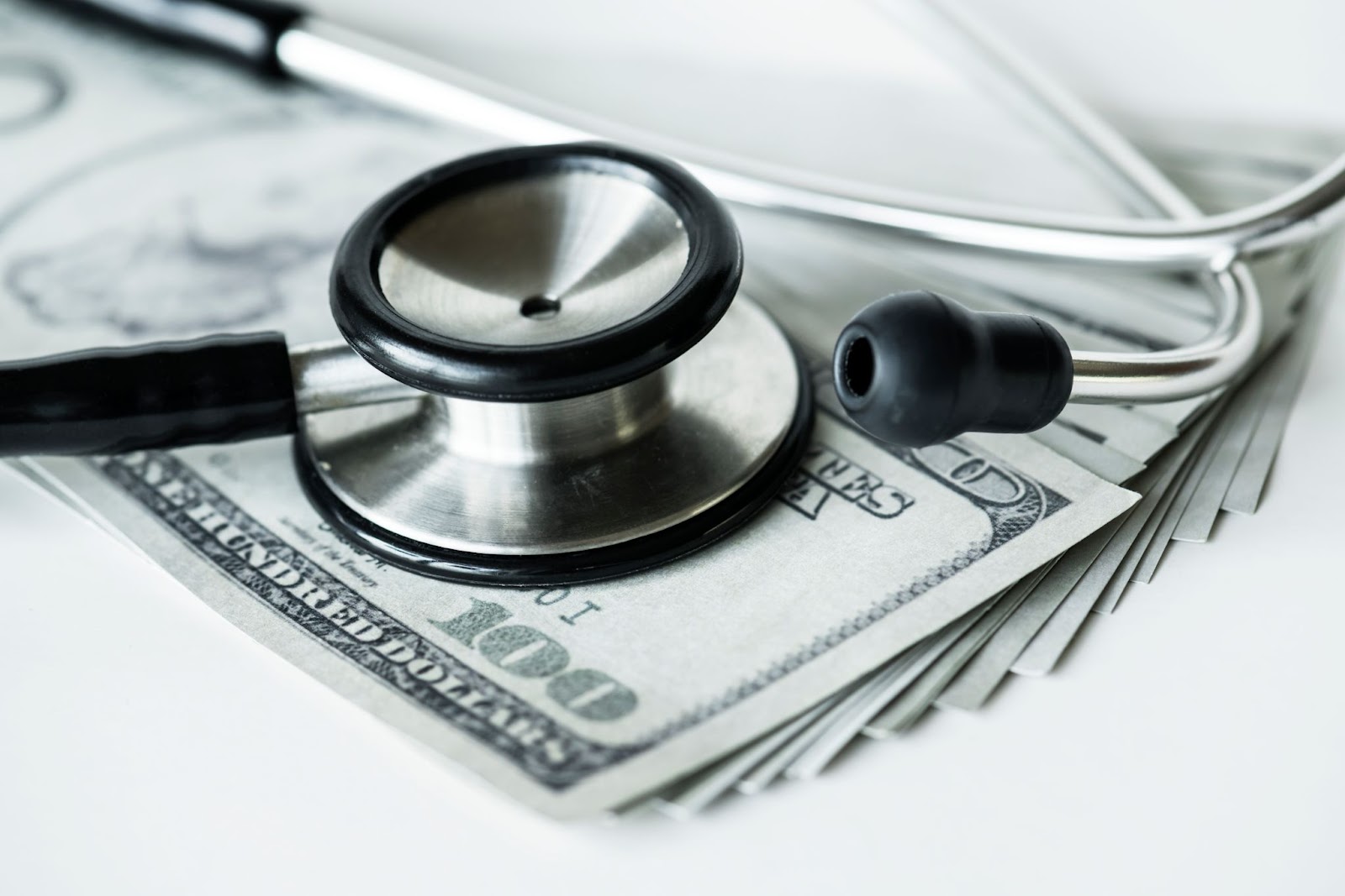 A stethoscope lying on top of a stack of dollar bills, symbolizing the cost of healthcare