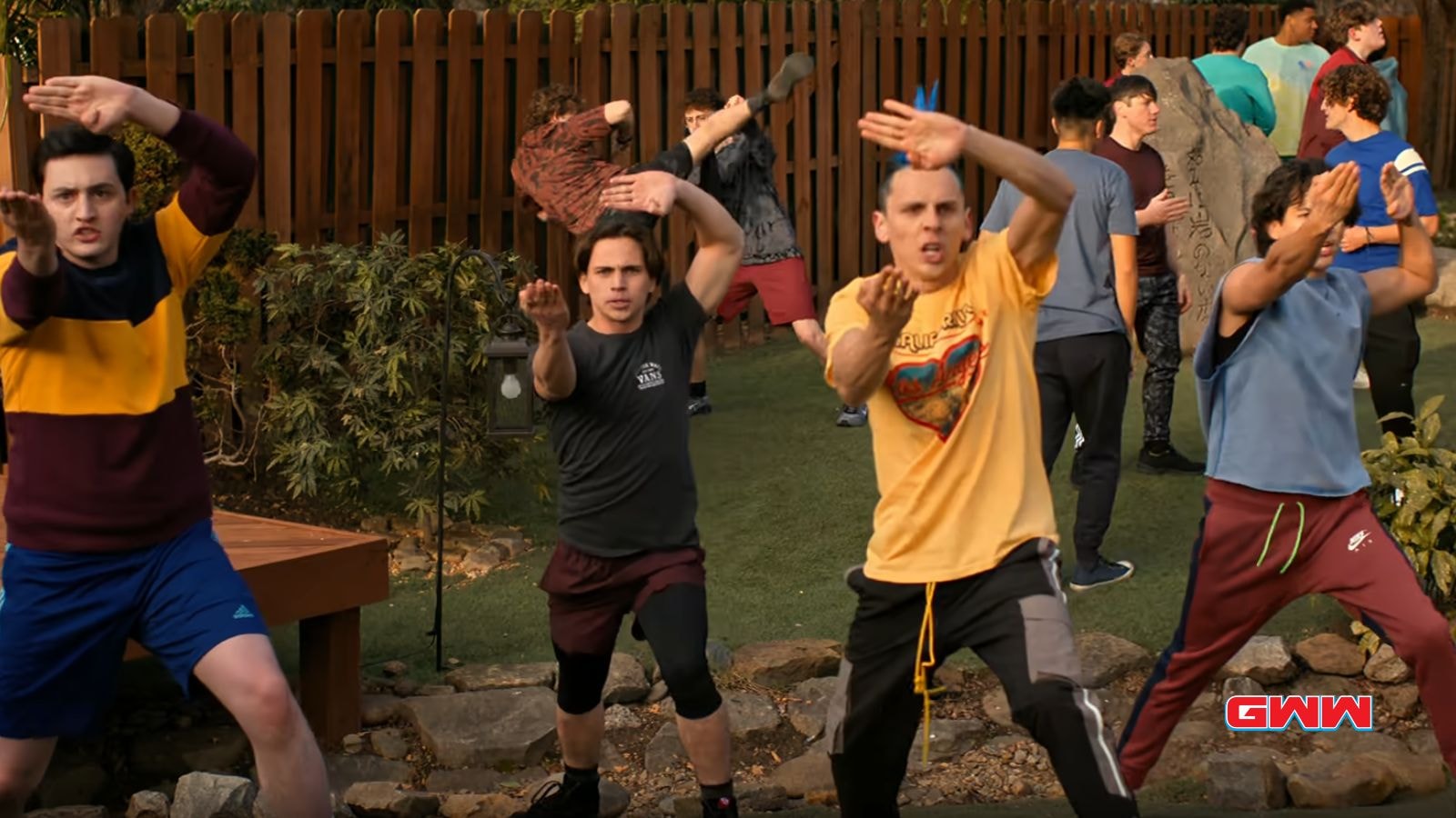 Group of karate students practicing martial arts moves in a yard.