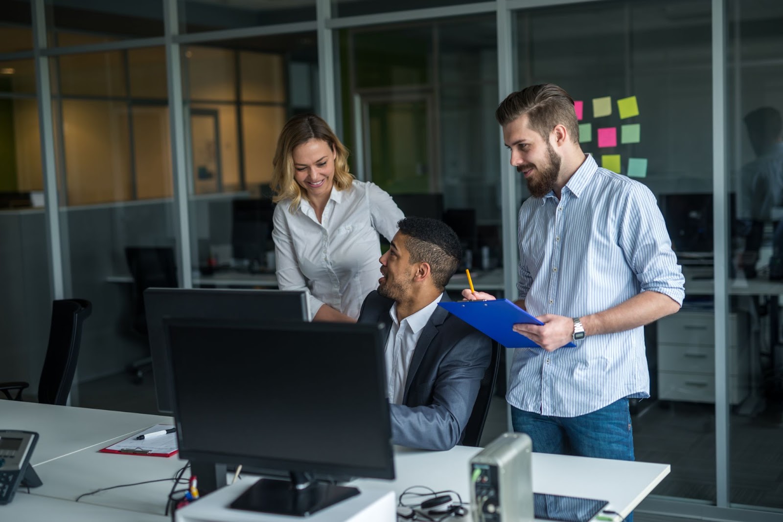 Three people collaborating on a project next to a computer. 