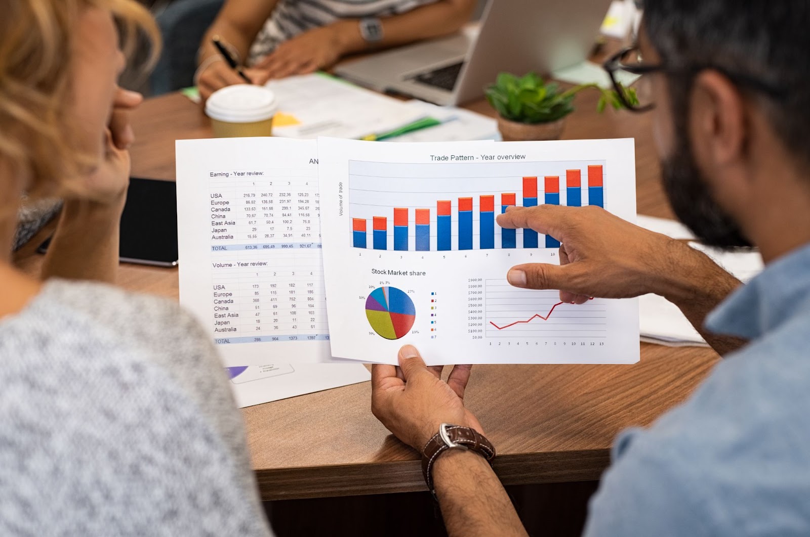 Businesspeople analyzing graphs and reports together, focused on financial data and ownership transparency.