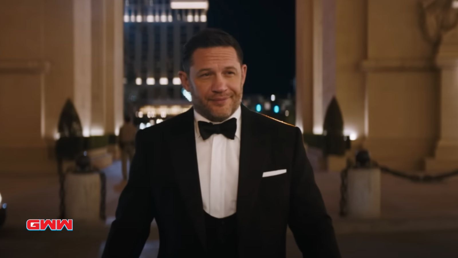 Eddie in a tuxedo smiling, standing in front of a grand building.