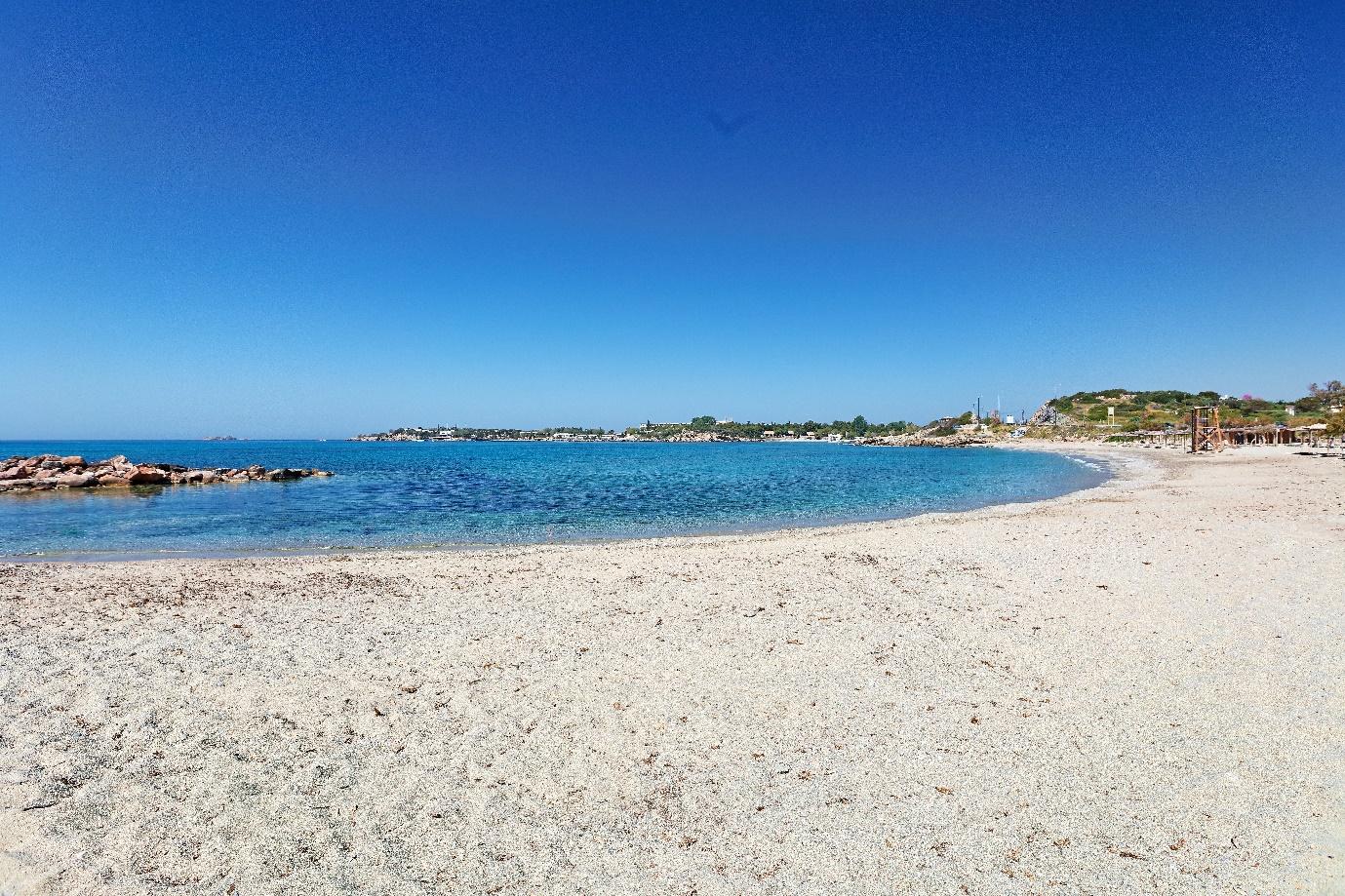 A beach with blue water and a blue sky

Description automatically generated