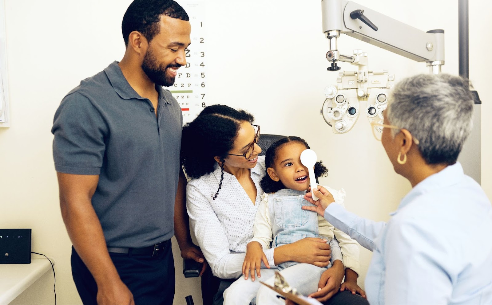 A family smiling while an optometrist discusses myopia control options for their child.