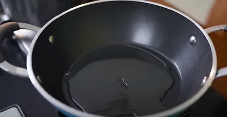 Heating oil in a pan to start preparing Suji ka Nasta.