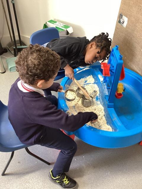 A child and child playing with sand

Description automatically generated