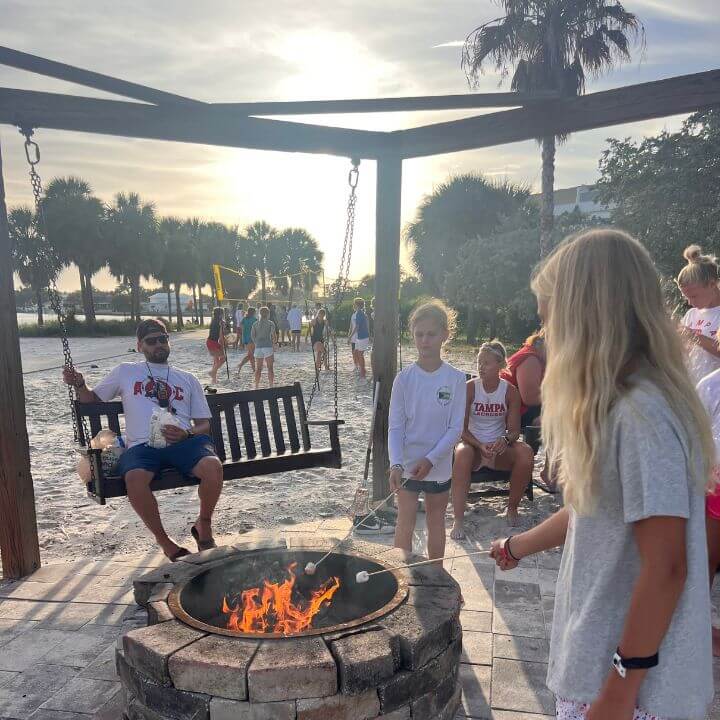 Young athletes at overnight sports camp roasting marshmallows over a bonfire on the beach