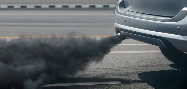 A car producing black smoke as it runs