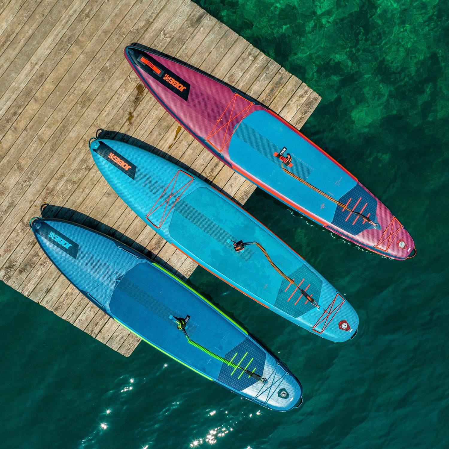 trois planches de stand up paddle sur un ponton en bois