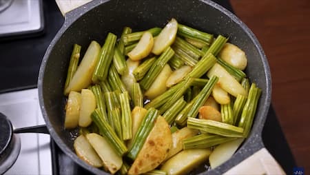 Cooking the drumsticks and potatoes until golden brown.