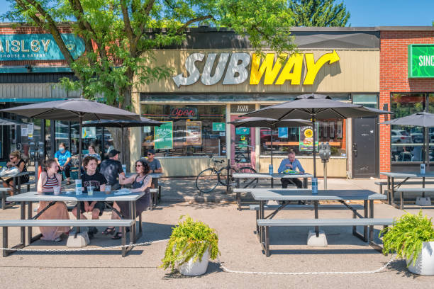 People eat outdoors on fast-food restaurant patio People eat outdoors on a Subway fast-food restaurant patio in Hamilton, Ontario, Canada on a sunny day. subway restaurant stock pictures, royalty-free photos & images