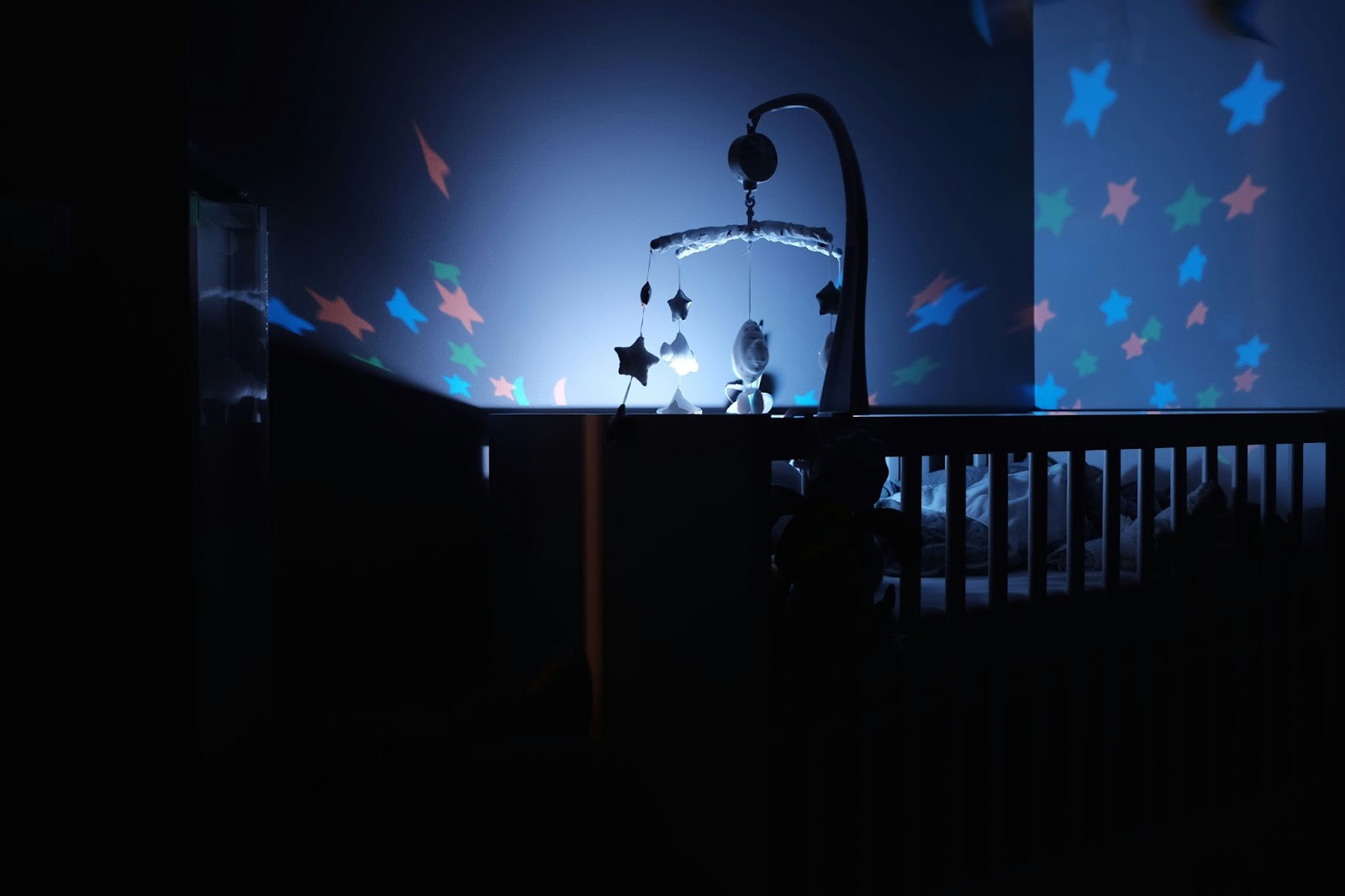 Dimly-lit baby room with a crib and starry lights lamp