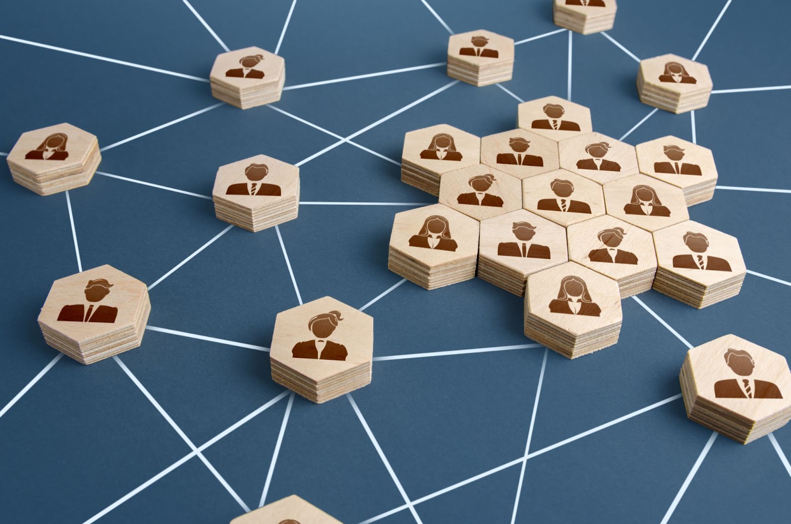 A network of connected people symbolized by geometric wooden tiles etched with human silhouettes, placed on a chalk-drawn web, depicting the future of corporate compliance.