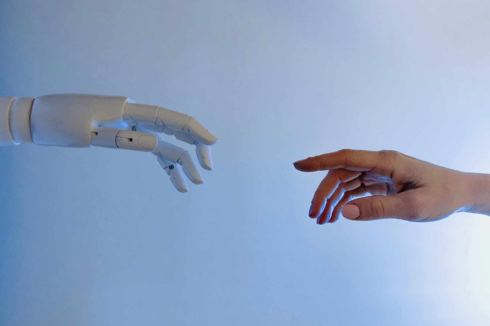 a robotic hand reaching a human hand against a blue background