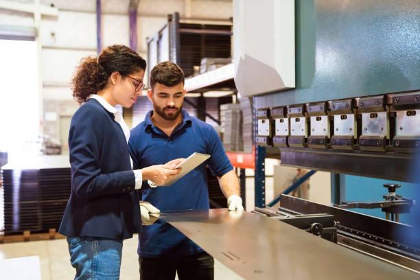 Manager and worker working in factory Manager showing digital tablet to production worker. Male engineer is manufacturing sheet metal. Female inspector is on visit in factory. sheet metal fabrication stock pictures, royalty-free photos & images