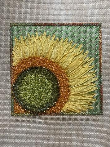 A sunflower embroidered on a fabric surface

Description automatically generated